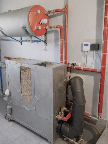 HERKULES INOX 20 kW w Brzusce – boczny widok kotła i czarnego przewodu spalinowego